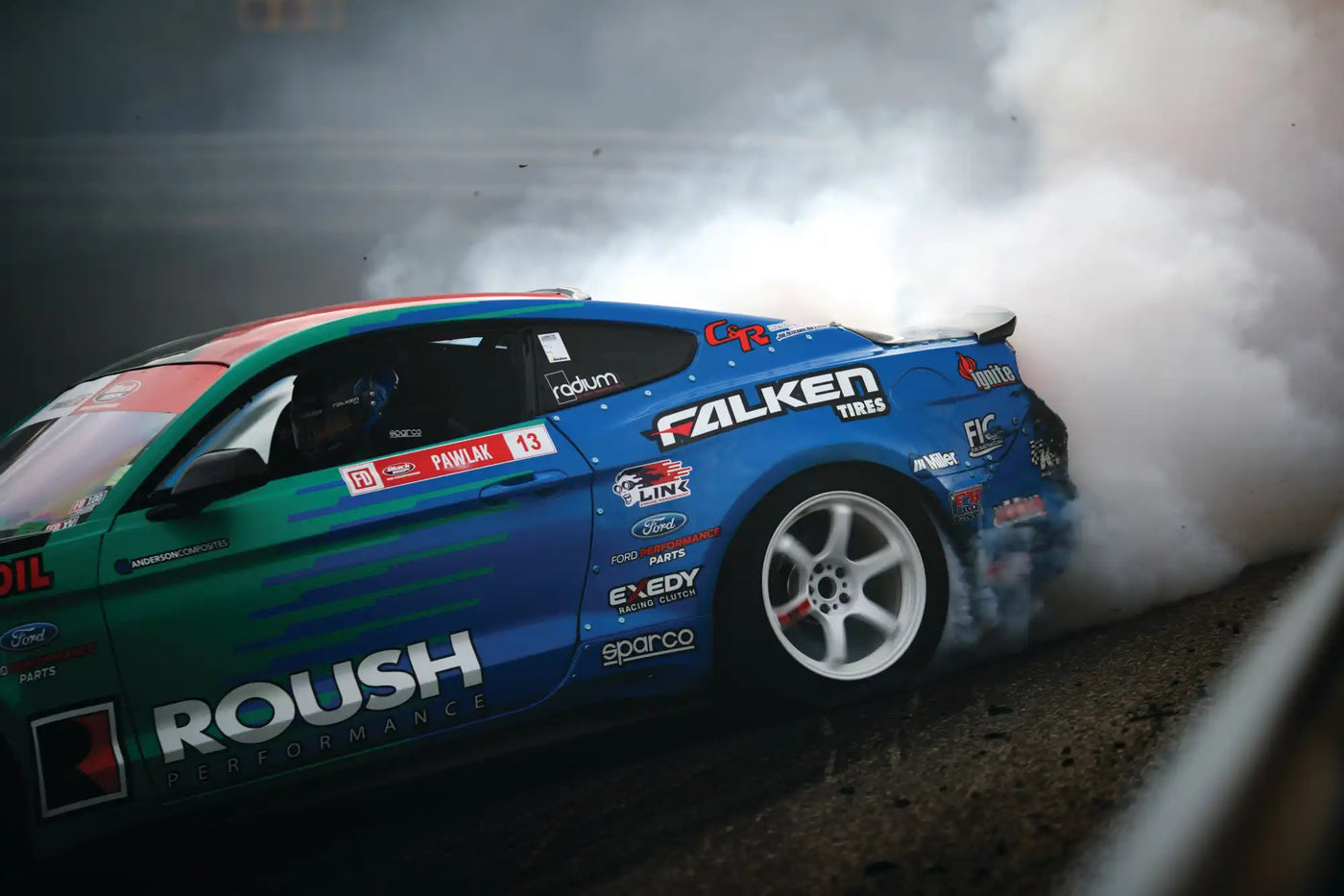 Drifting race car with sponsor decals.